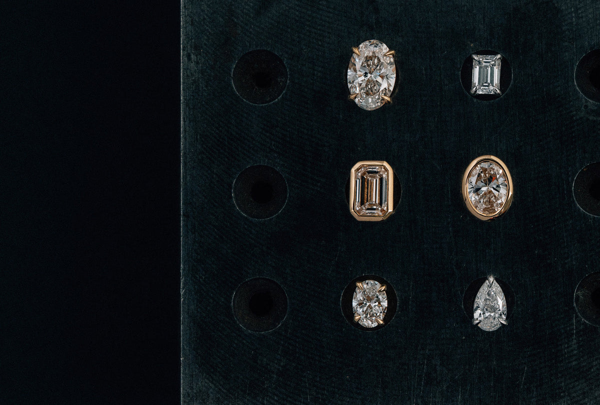 18k yellow and white gold solitaire stud earrings set with oval, emerald, and pear cut natural white diamonds in a claw and bezel setting.