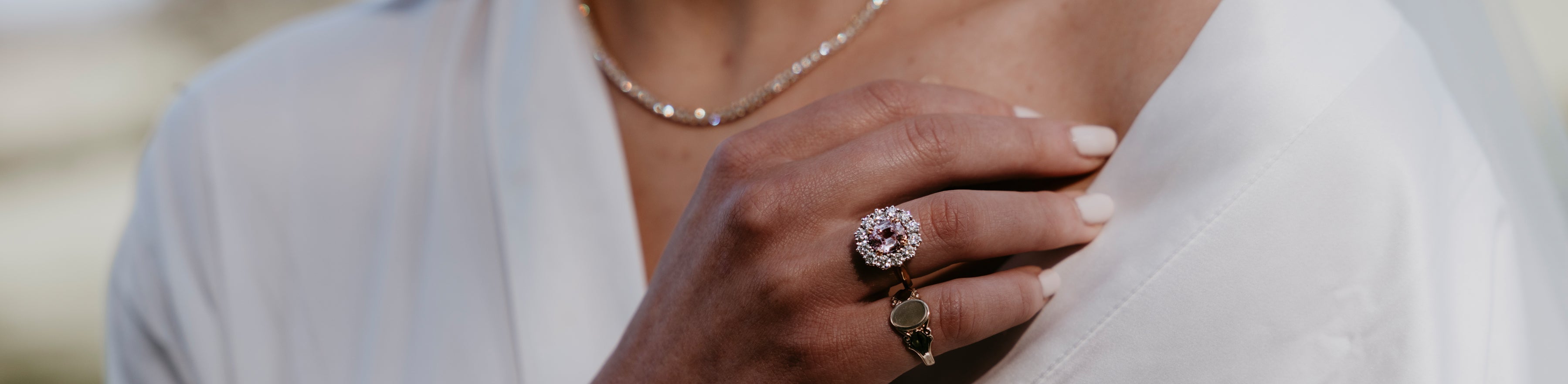 Bride wearing vintage yellow gold signet ring and pink sapphire cluster ring with a tennis necklace on wedding day.