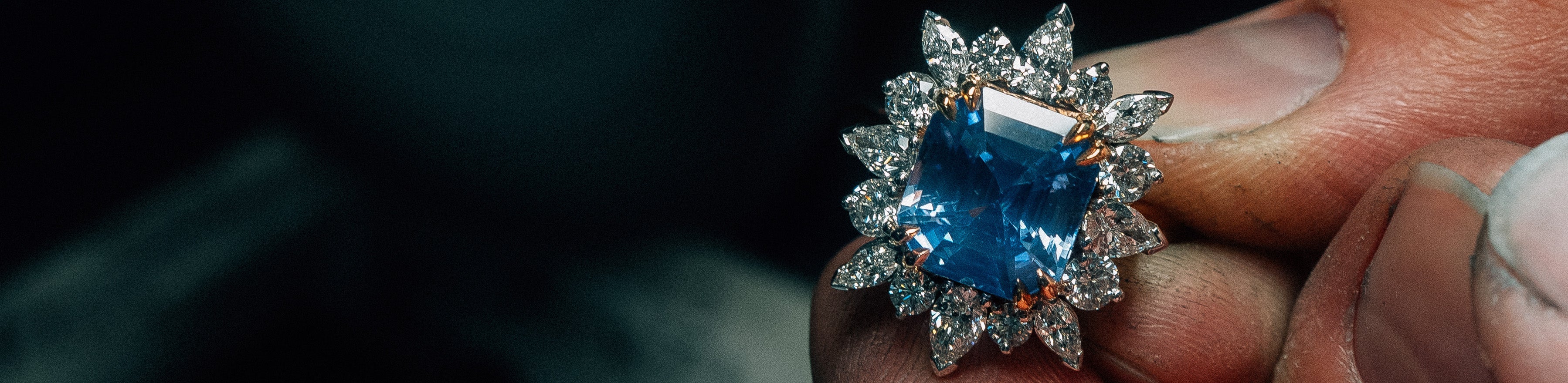 Jeweller holding large Ceylon sapphire and diamond cluster dress ring.