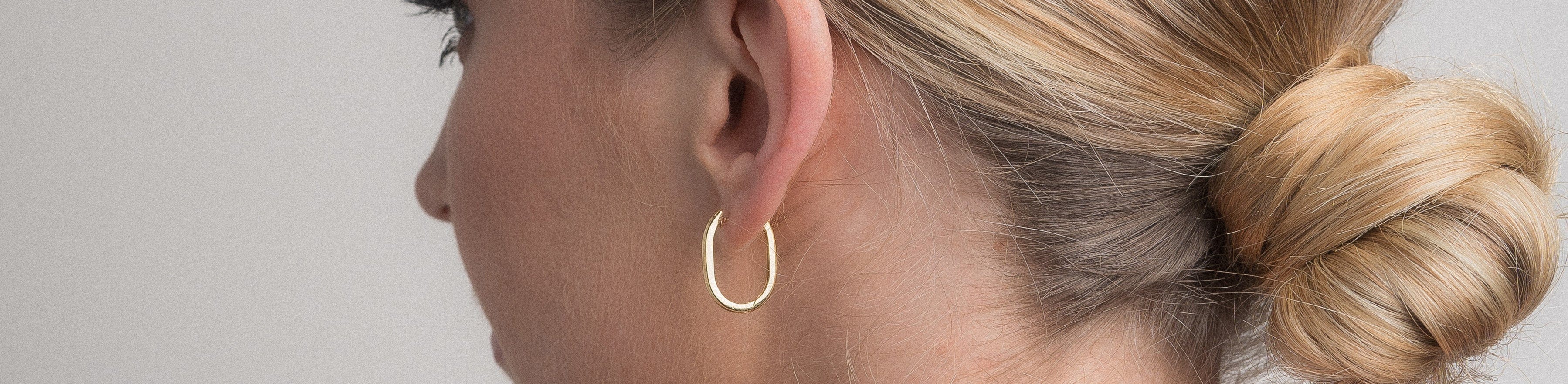 Model wearing plain gold huggie earring.