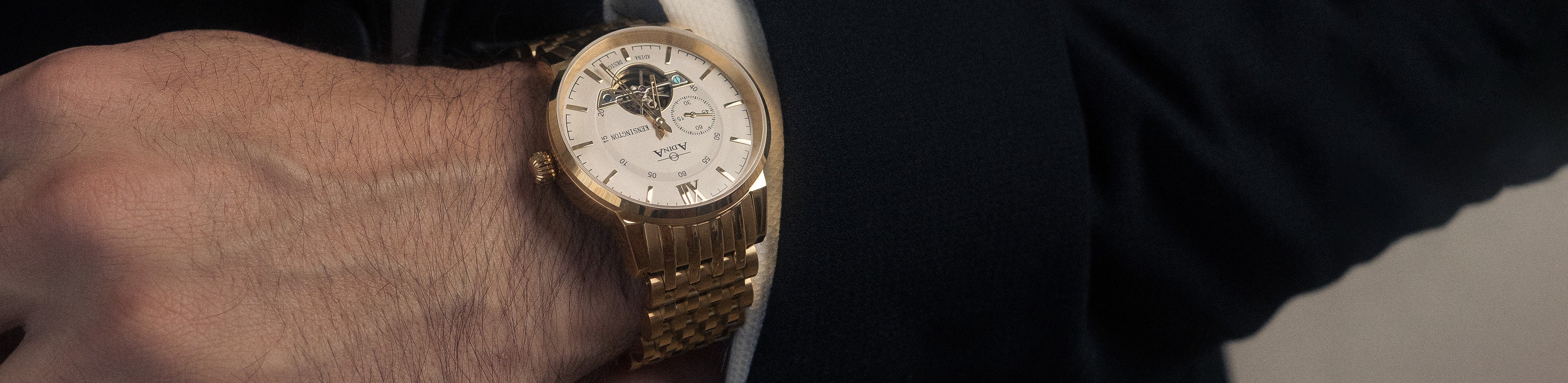 Men in suit with golden Adina watch on wrist.