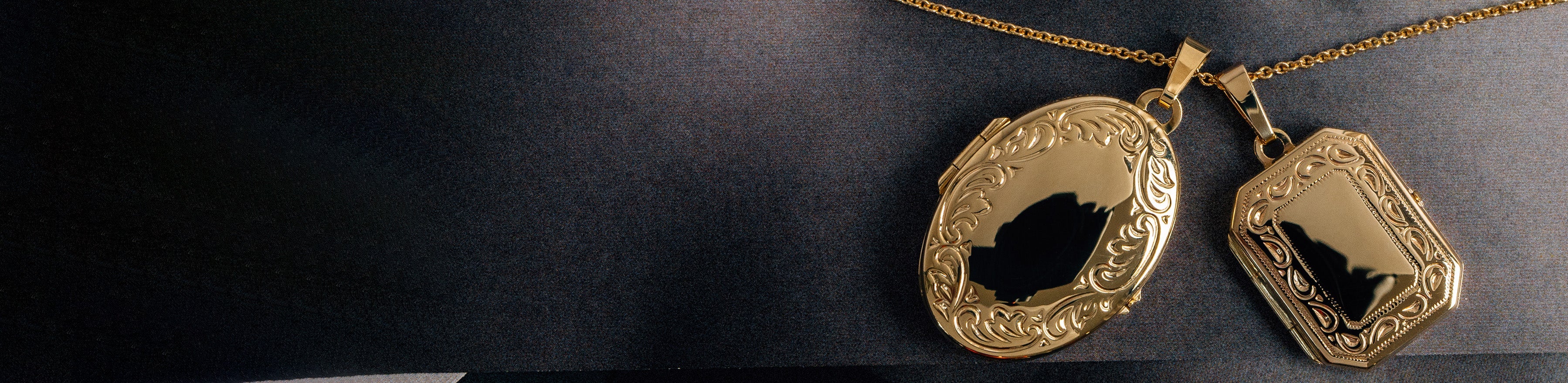 Yellow gold locket pendants with scroll engraving.