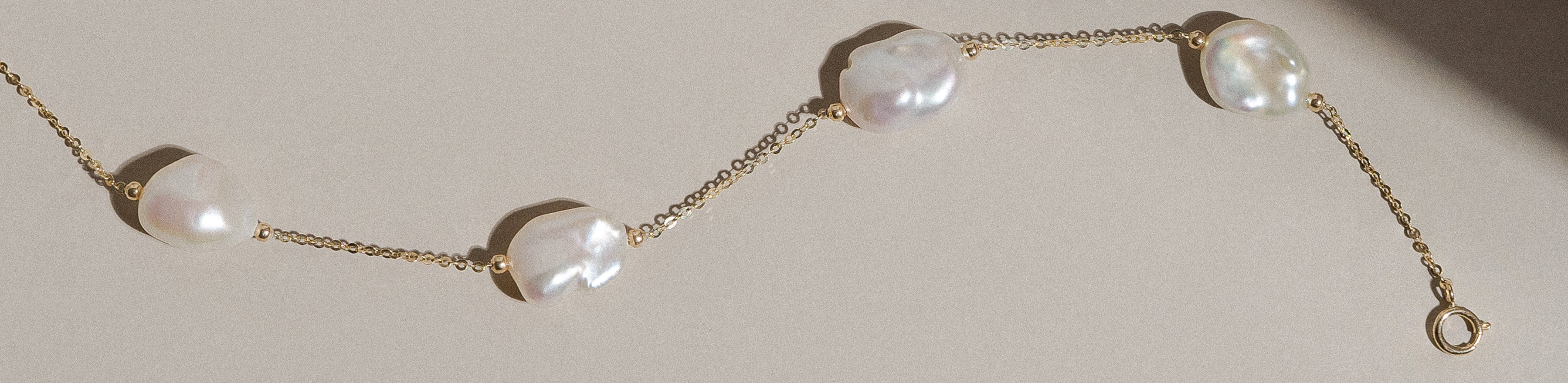 Freshwater keshi pearl yellow gold necklace on a cream background.
