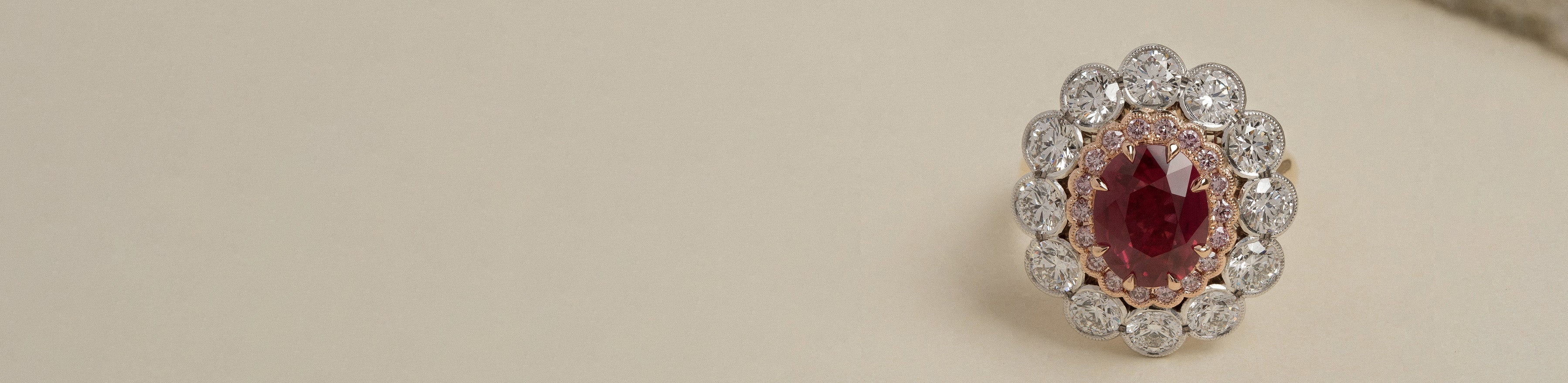 Yellow, white and rose gold oval cut ruby, pink and white diamond cluster ring on a cream background