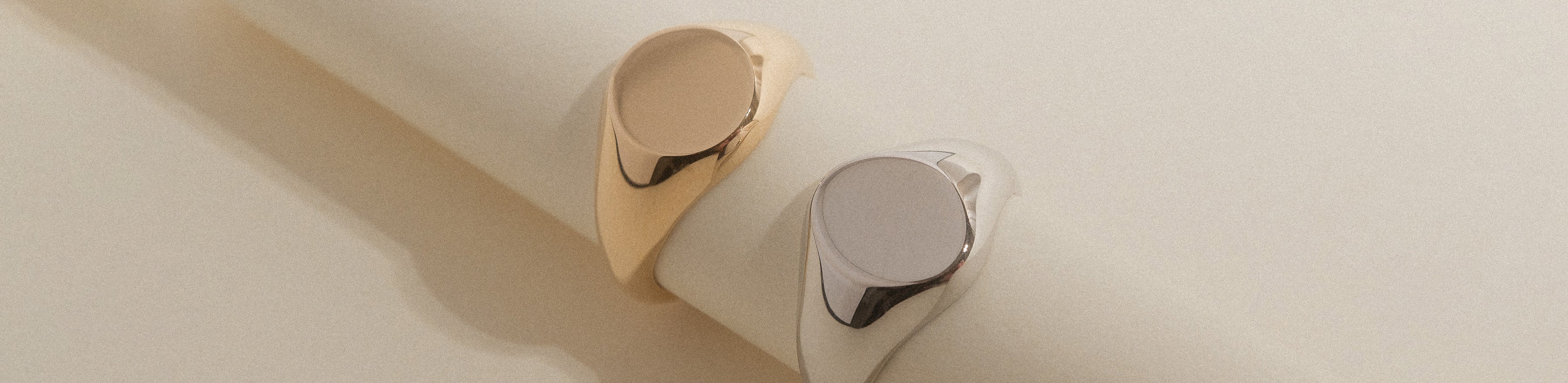 Yellow and white gold round faced signet rings on a cream roll.