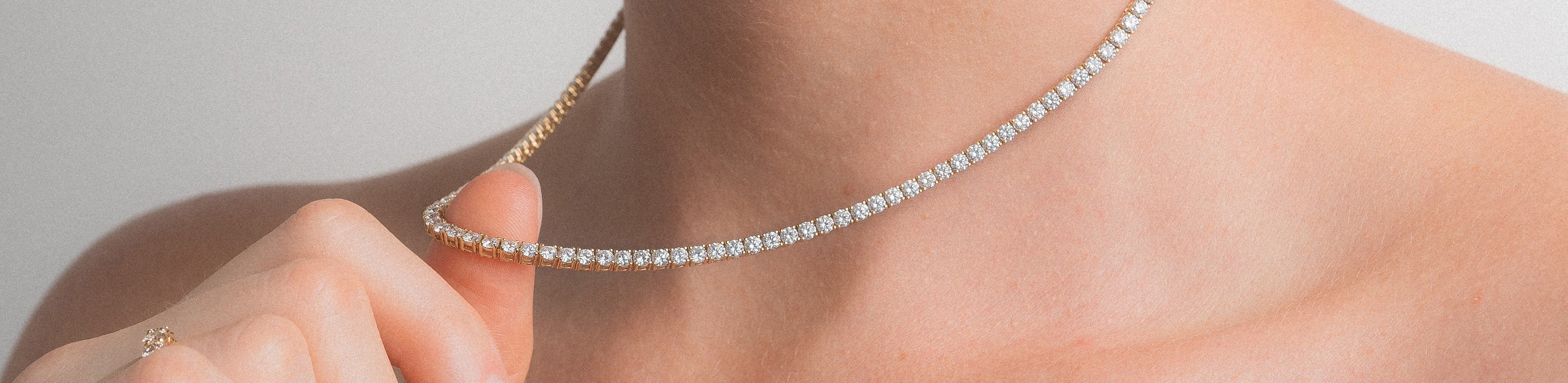 Yellow gold diamond set tennis necklace on model.