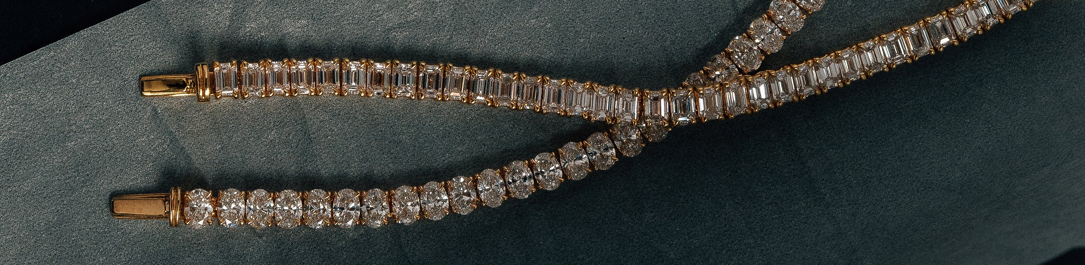 Yellow gold oval and emerald cut natural diamond tennis bracelet on silver paper.