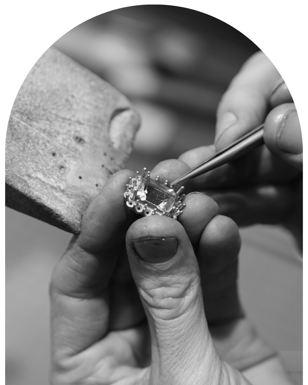 Jeweller at workbench using tweezers to bend claw on cluster style ring.