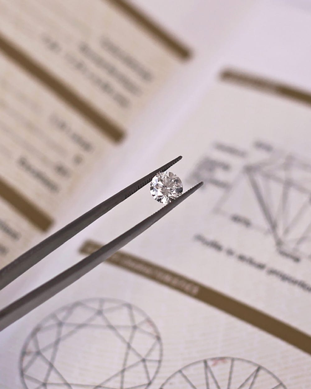 Tweezers holding round brilliant cut white diamond above GIA diamond certificate.