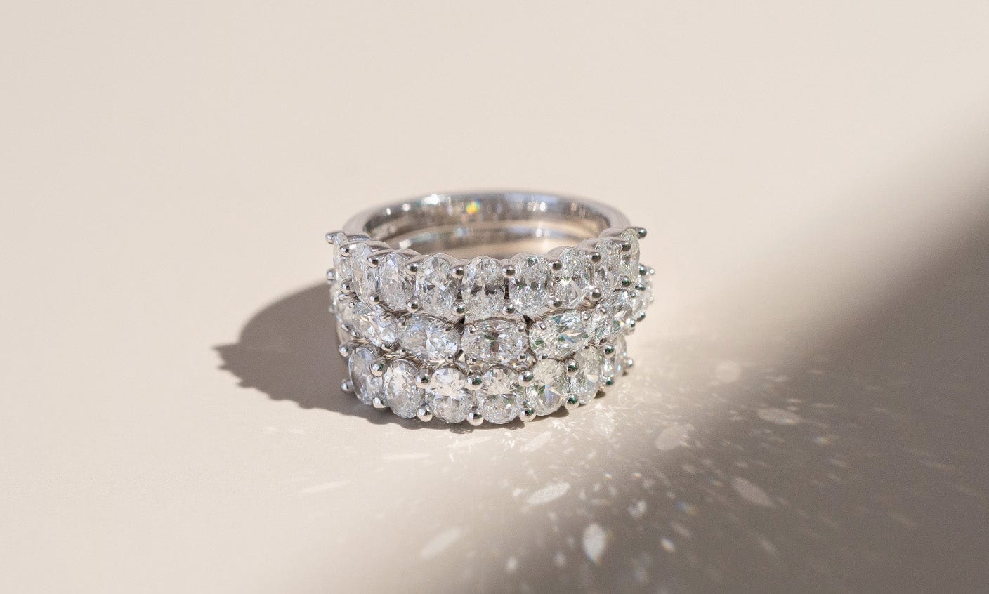 Three white gold oval diamond rings stacked on top of one another.