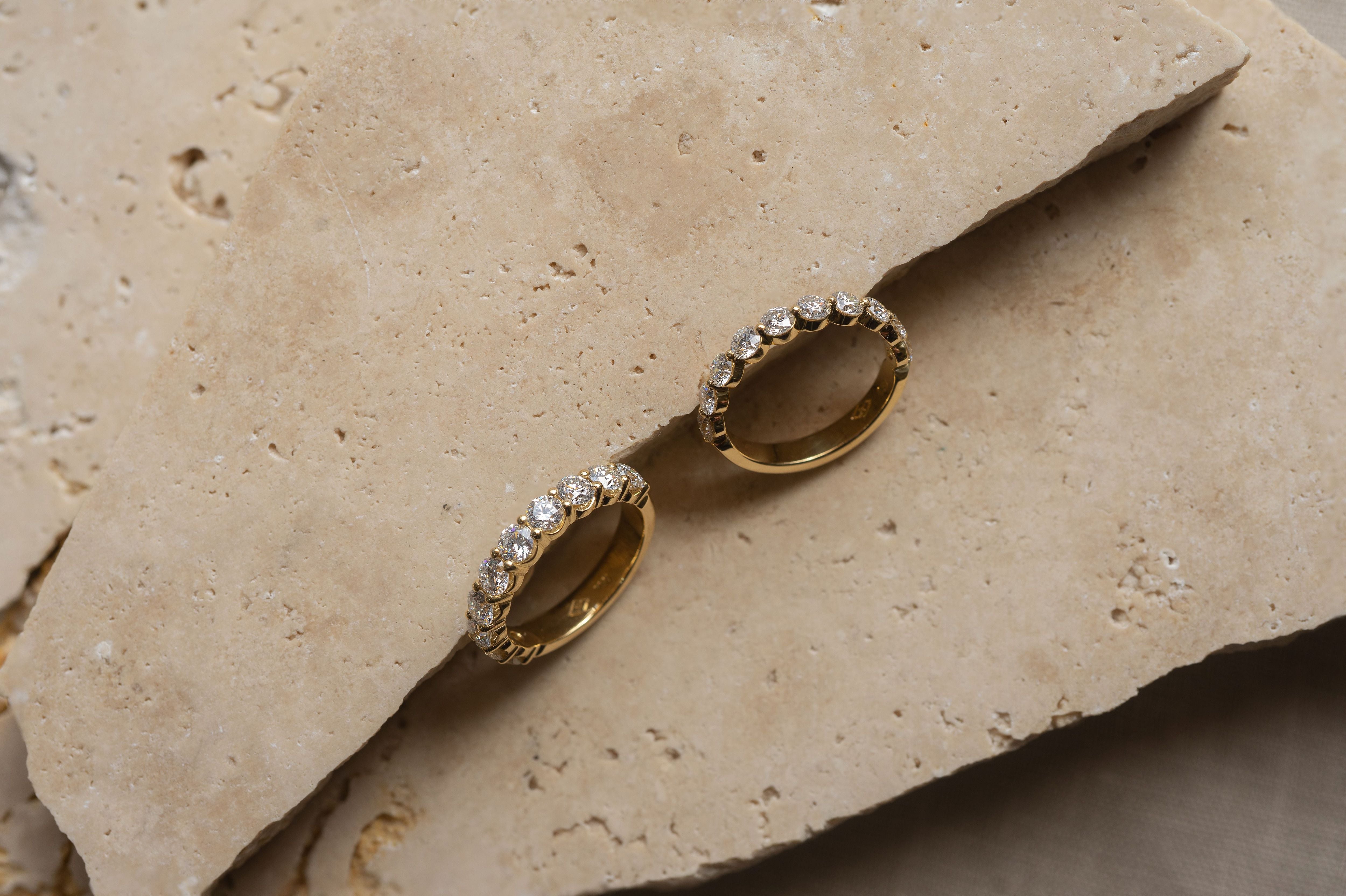 Yellow gold diamond set rings photographed on travertine background.