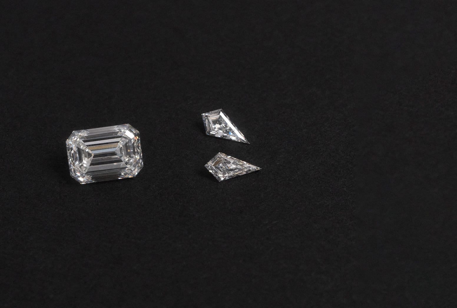 Emerald cut and kite cut natural white diamonds on black background.