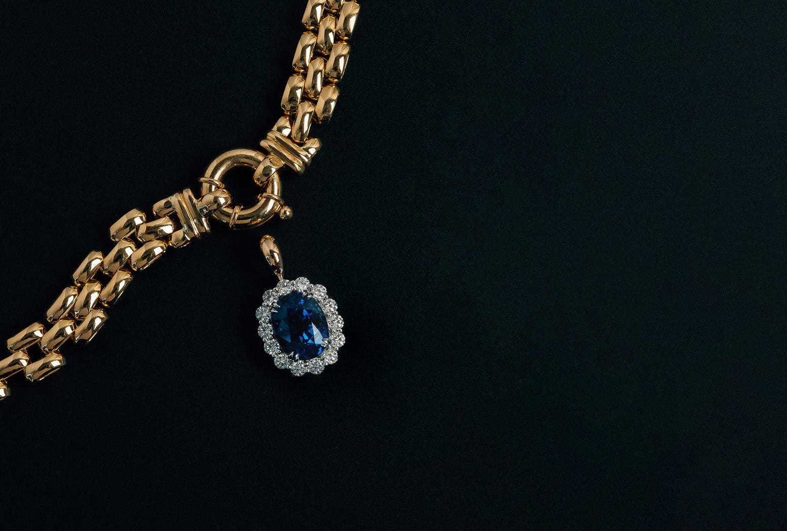 18k yellow and white gold cluster pendant on a fancy link chain with oval cut blue sapphire and round brilliant cut white diamonds.
