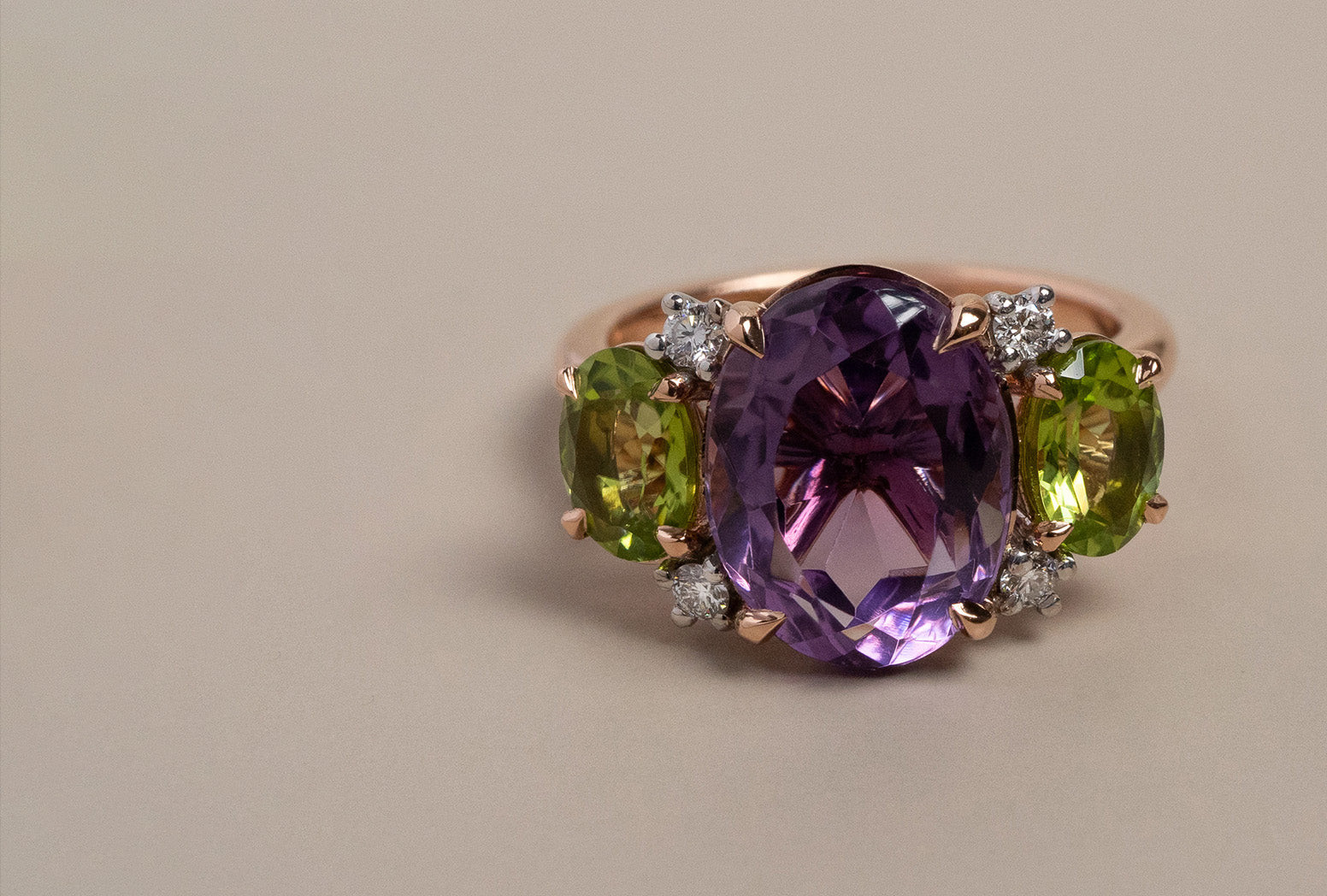 Rose and white gold trilogy ring with natural oval cut amethyst and peridot gemstones.