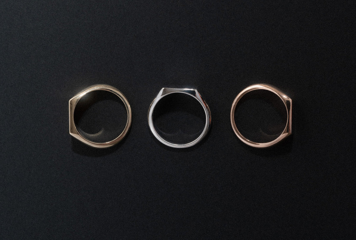 18k yellow, white and rose gold rectangular signet rings on black background.