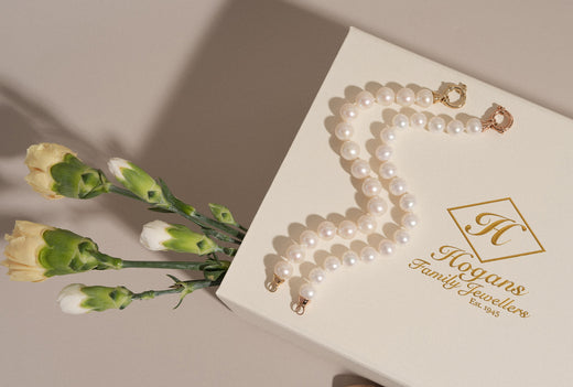 Yellow and rose gold pearl bracelets on a Hogans gift box with flowers.