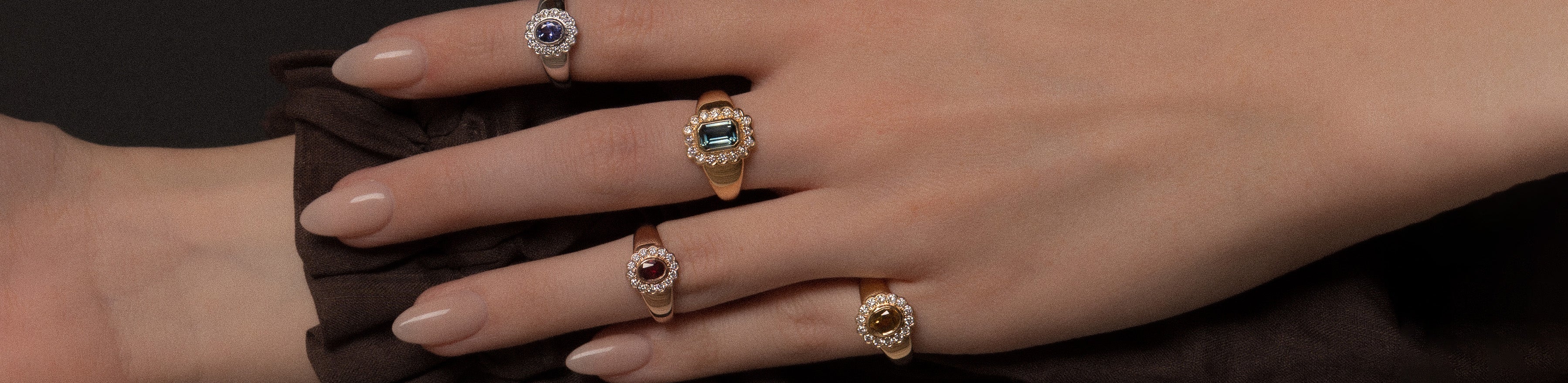 Yellow, rose and white gold multi-colour gemstone set daisy signet rings on a model hand.
