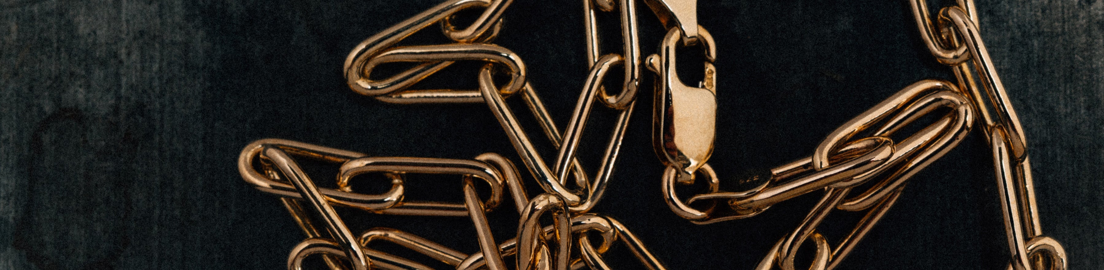 9k yellow gold paperclip link chain necklace on black background.