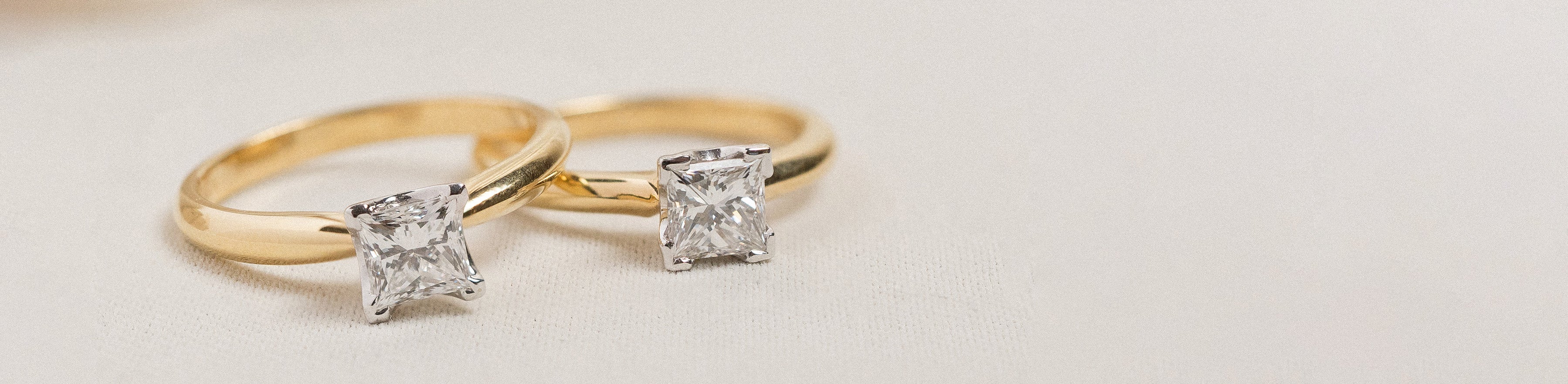 Yellow and white gold princess cut natural diamond solitaire rings on cream background.