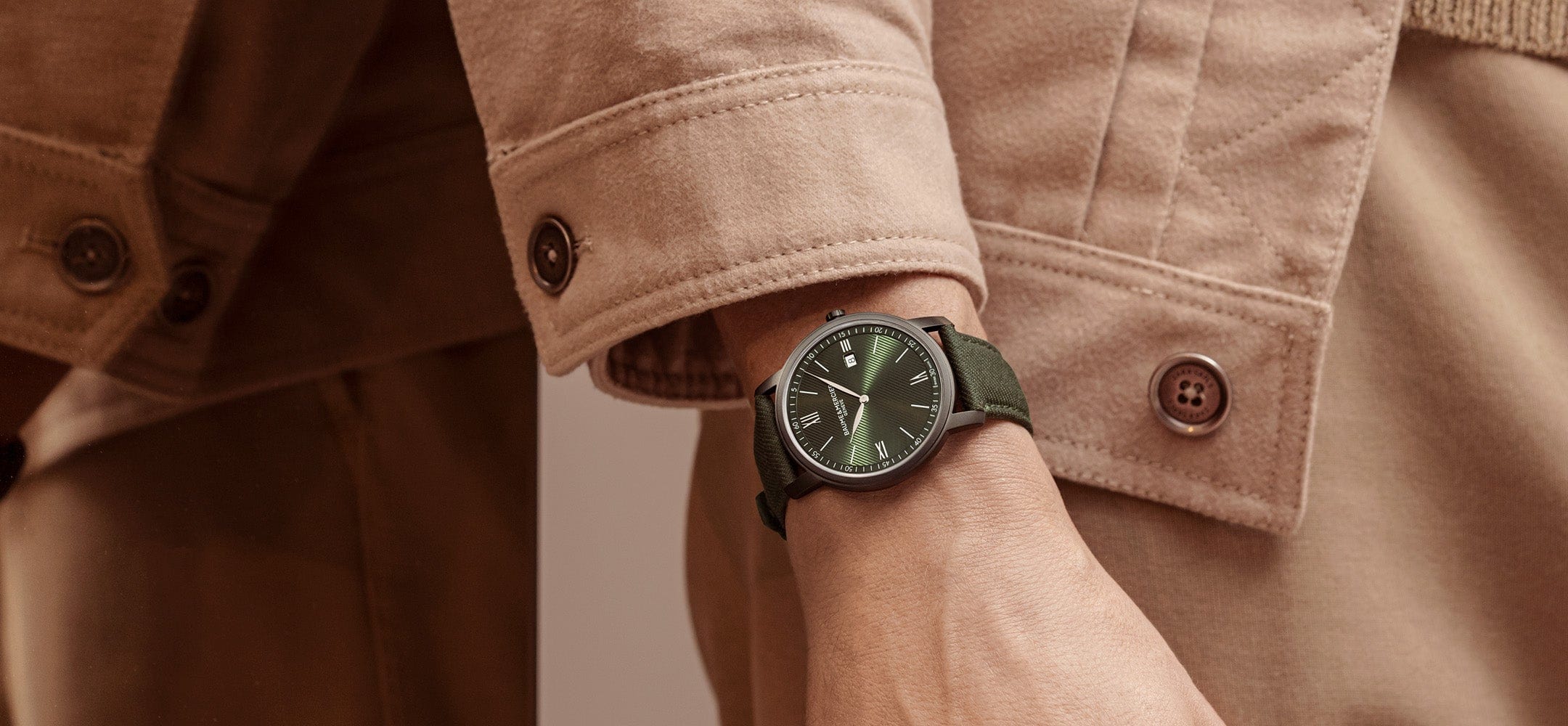 Male model wearing Baume & Mercier 10766 khaki coloured watch and camel coloured jacket.