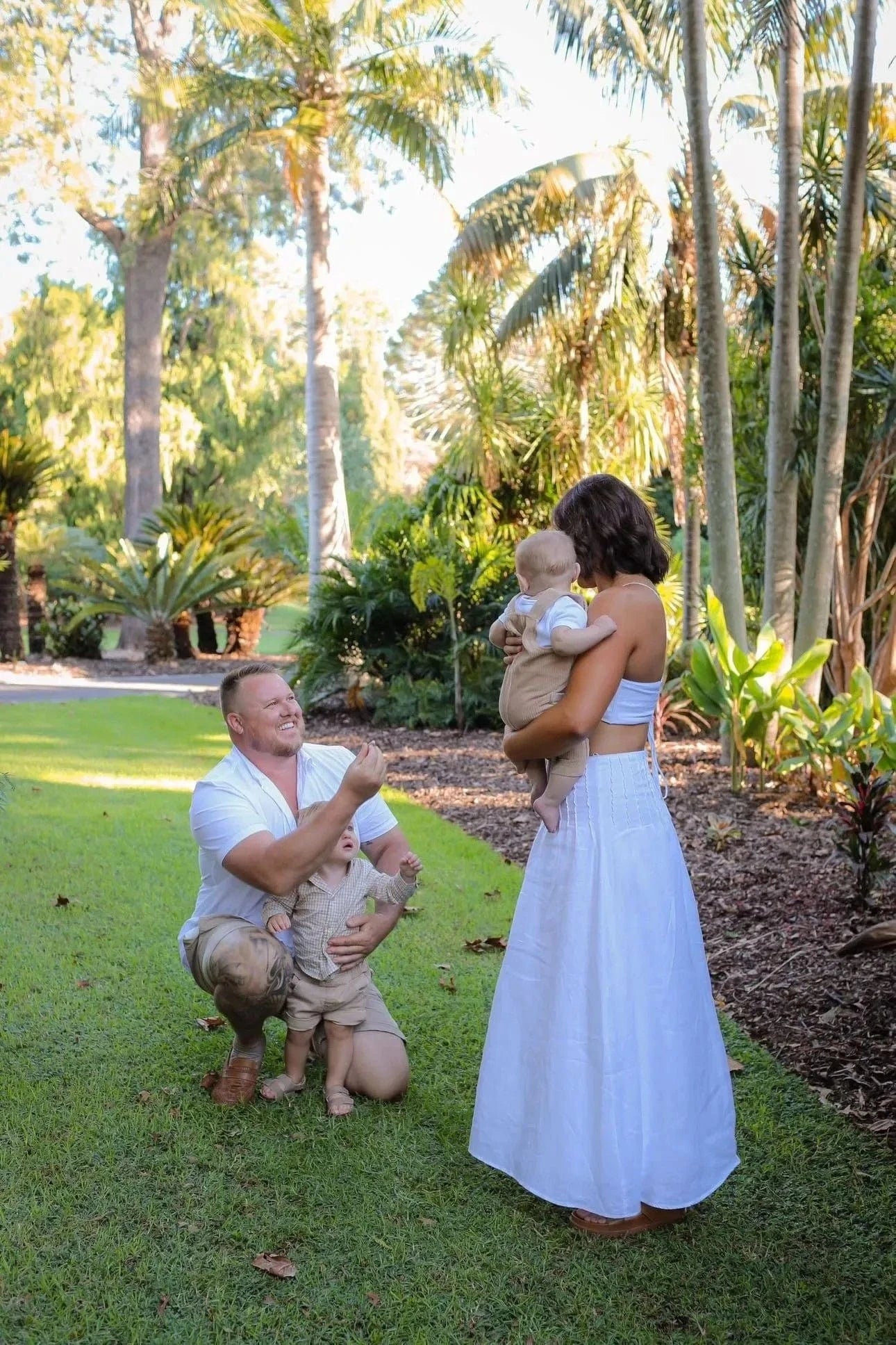 Couple proposing in park with children.