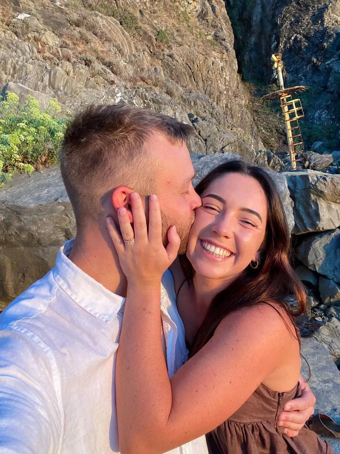 Couple posing for proposal photo by the beach.