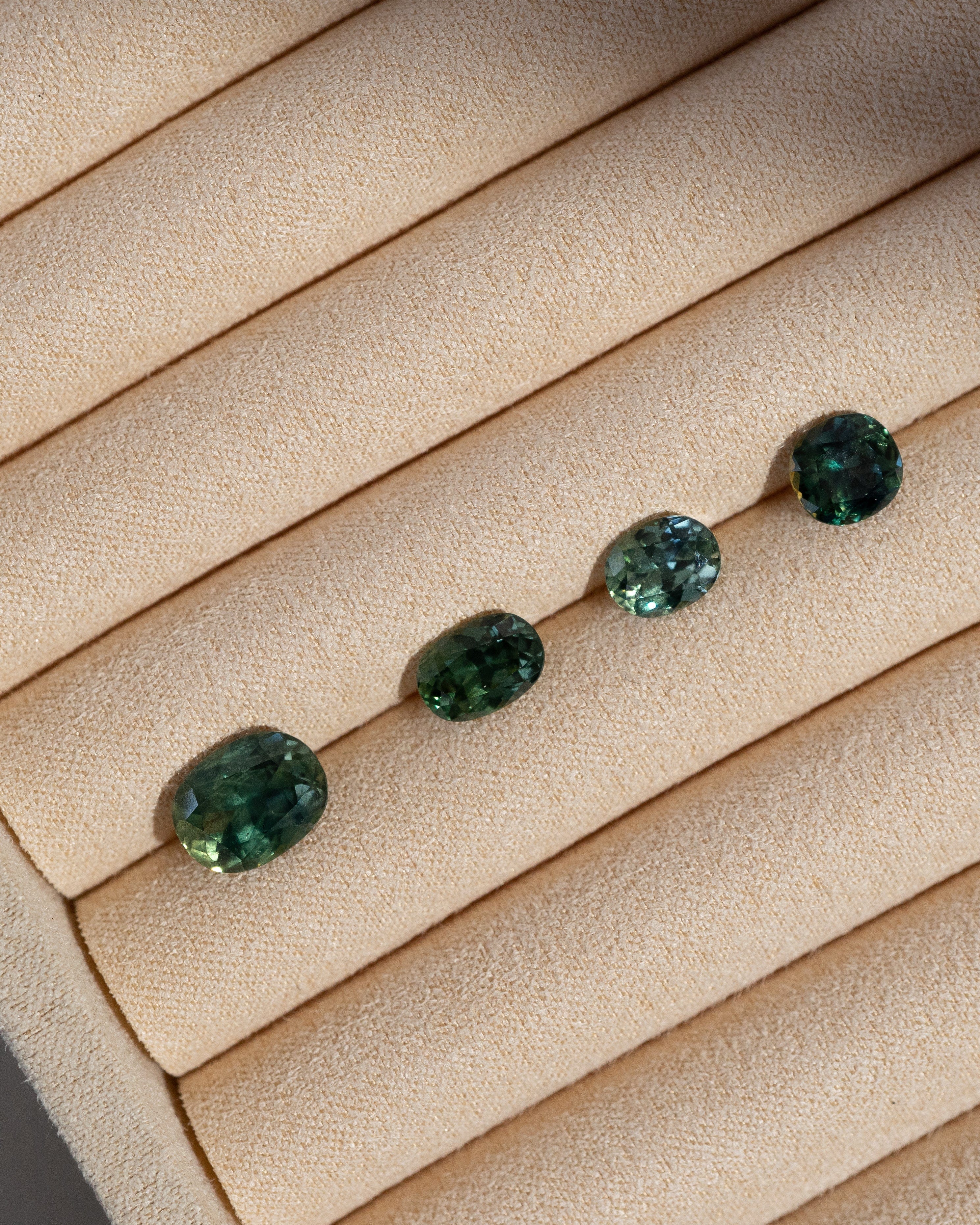 Four loose Australian sapphires on beige jewellery tray.