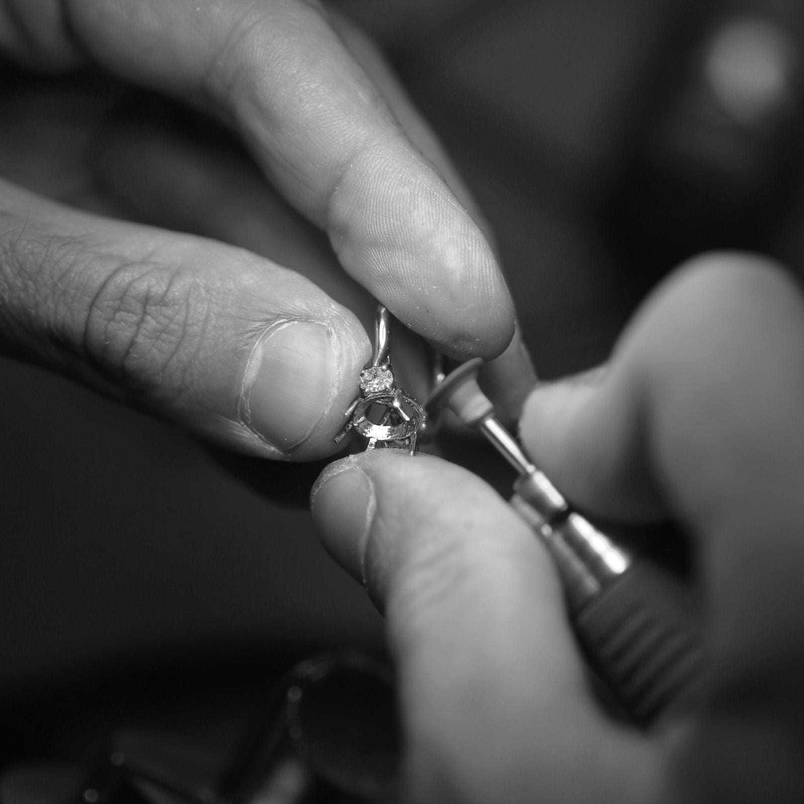 Jeweller using rotary tool to repair diamond ring.