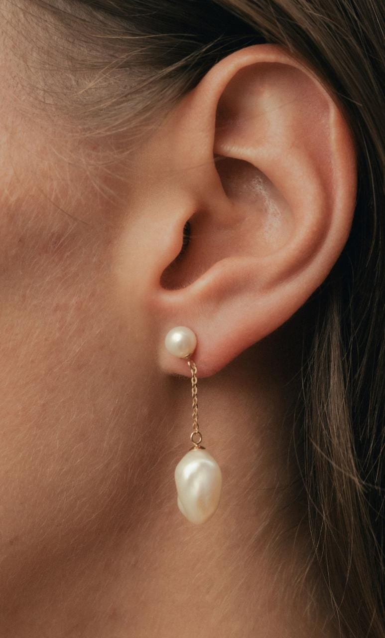 Side profile of woman wearing yellow gold freshwater & Keshi pearl drop earrings.