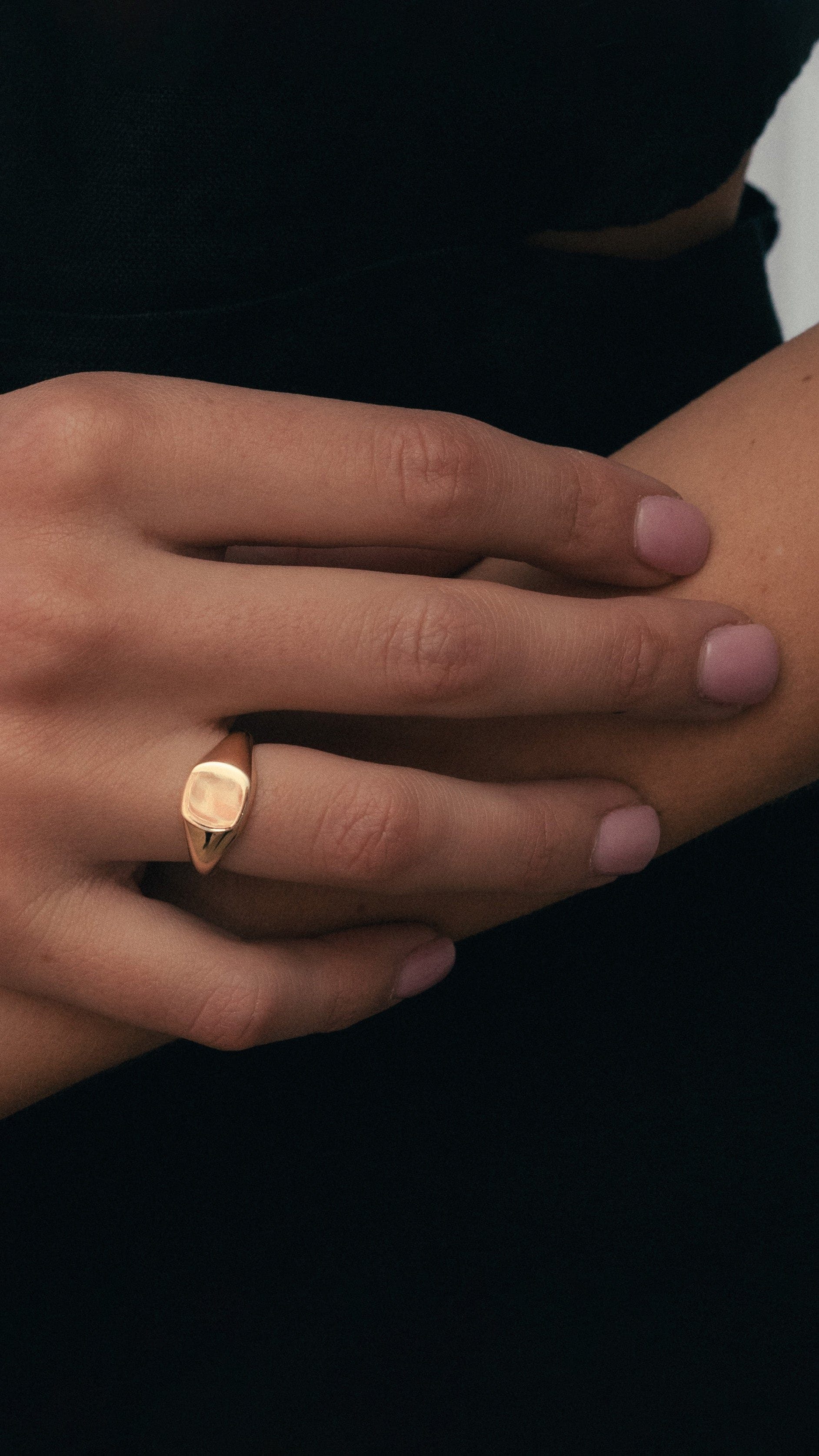 Model wearing yellow gold cushion signet ring and yellow gold diamond huggie band