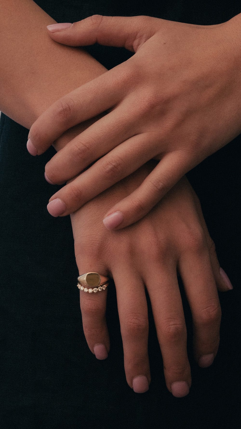 Model wearing yellow gold cushion signet ring and yellow gold diamond huggie band