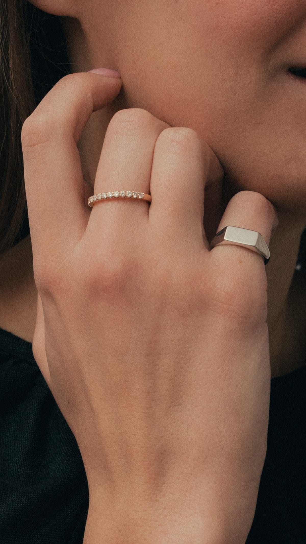 Model wearing white gold rectangular signet ring and rose gold diamond set band